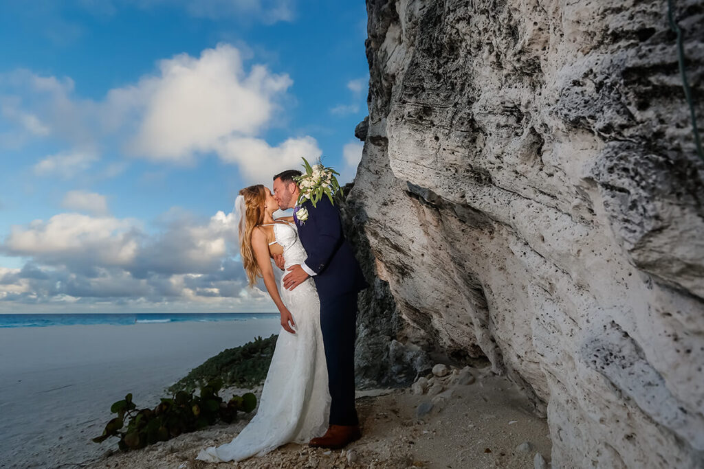 Bride and groom kissing next cliff and ocean.