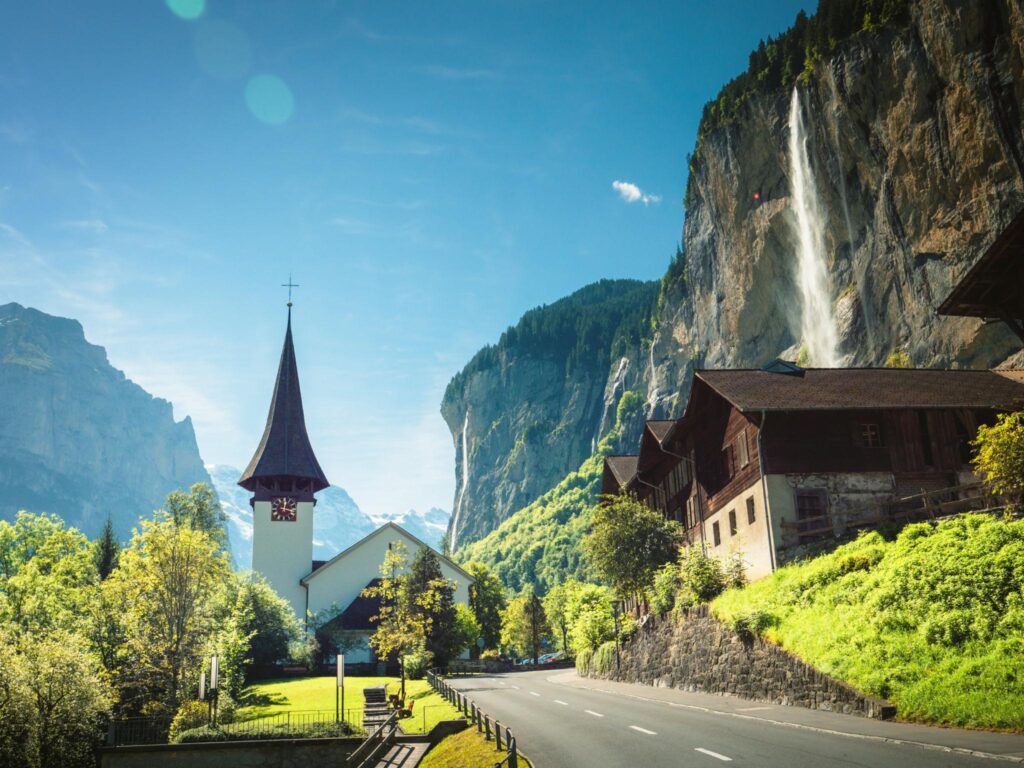 Waterfalls cascading down sheer cliffs into the green Lauterbrunnen Valley in the Swiss Alps