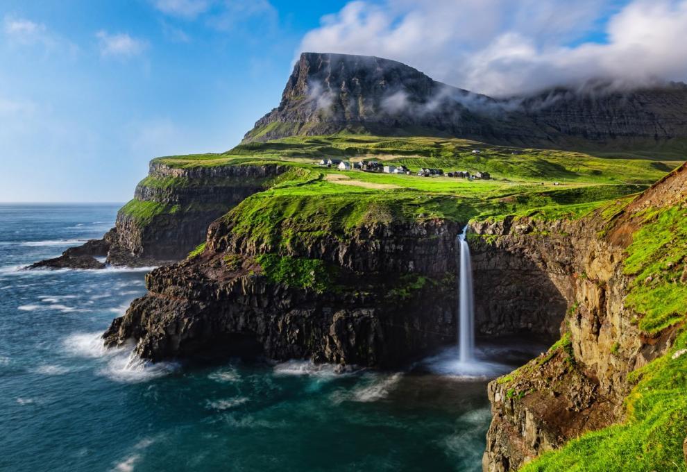 The Múlafossur waterfall plunging from emerald cliffs into the North Atlantic in the Faroe Islands